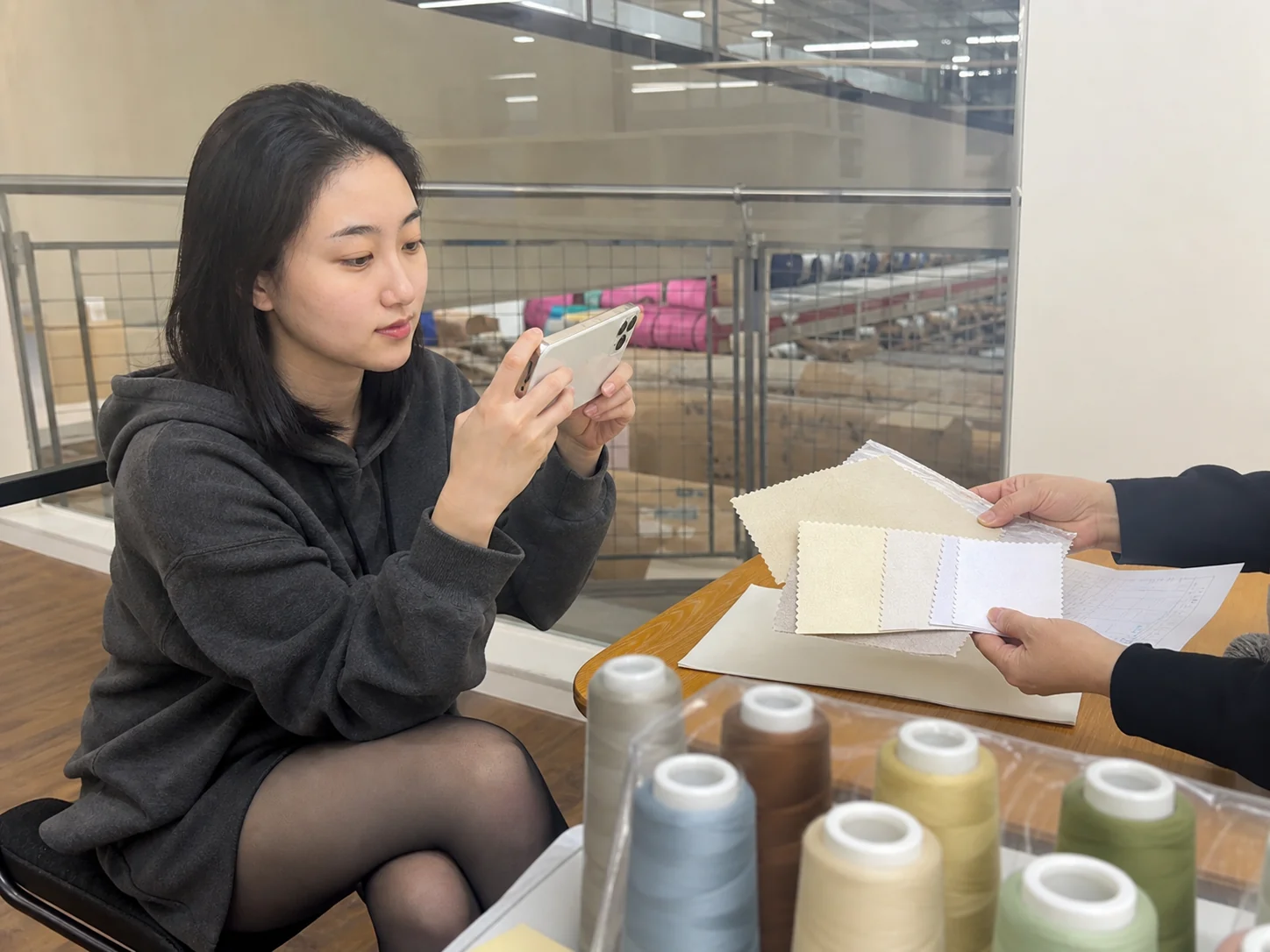 自媒体拍摄人员记录绣线、底布样片与批次资料交接的手机场景