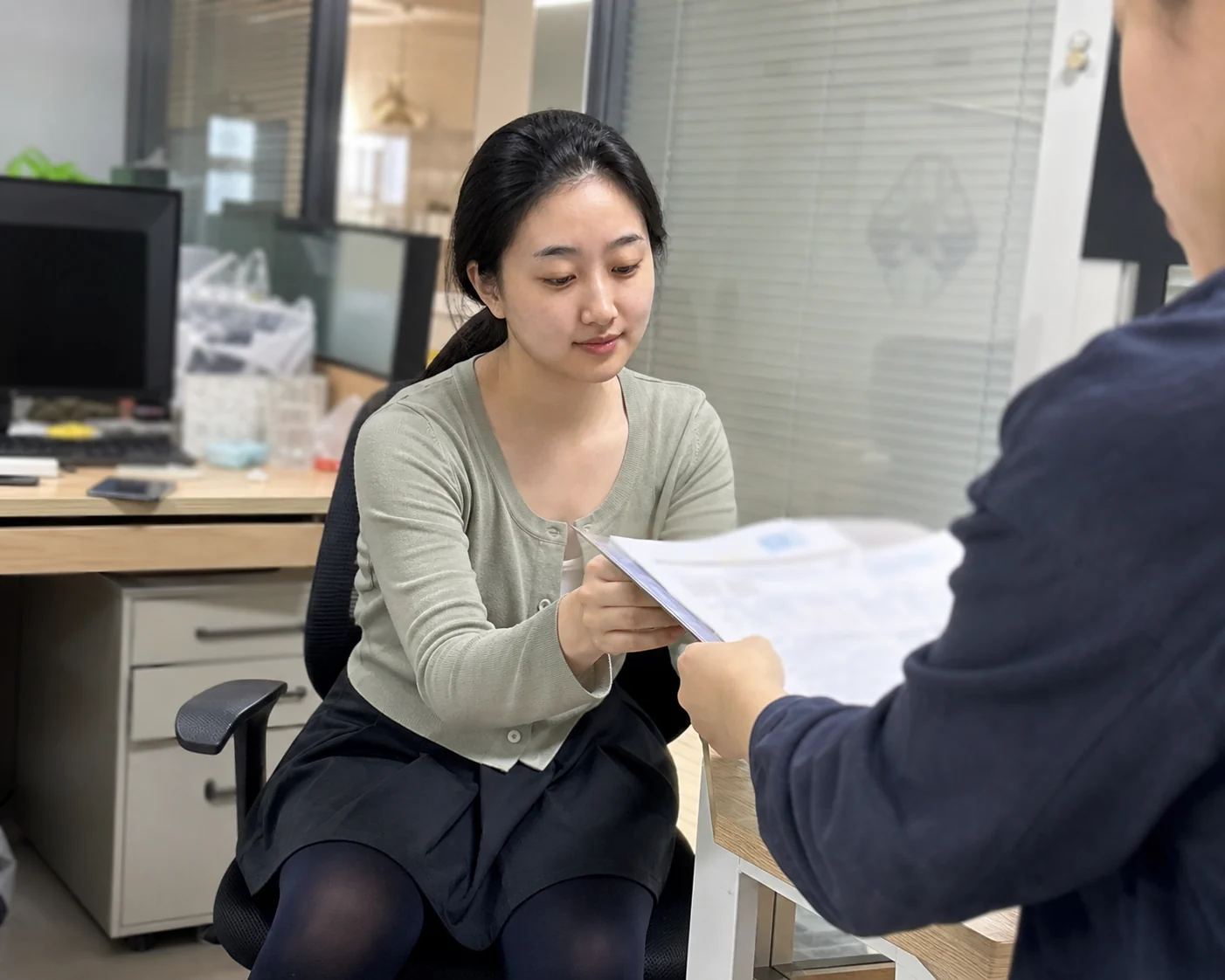 自媒体拍摄人员记录哑粉纸代工来料批次与样品资料交接的手机场景